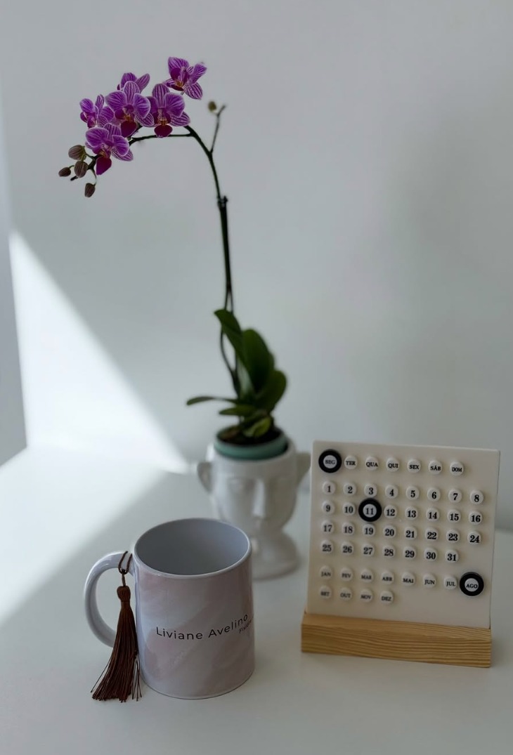 Orquídea, caneca Liviane Avelino e calendário na mesa